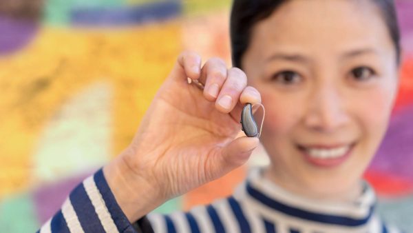 woman holding signia pure charge&go ix hearing aid between her fingers new signia ix hearing aid
