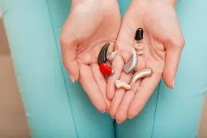 what to know when buying hearing aids hand holding different kinds of hearing aids