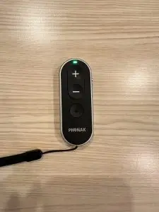 used phonak remote control with green light on laying on table