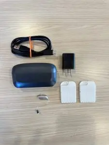 used resound vivia hearing aid with charger, cord, wall plug, and wax guards